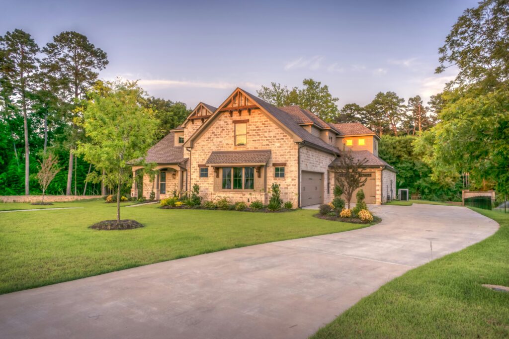 pexels-photo-259588-259588 Elegant stone family home surrounded by trees, lush lawn, and vibrant garden.